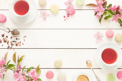 pink fruity tea and pastel french macarons cakes on rustic white wooden background. dessert in a garden. flat lay composition (from above, top view). free text space.