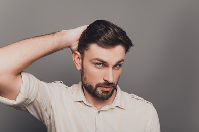 portrait of handsome serious young man combing his hair