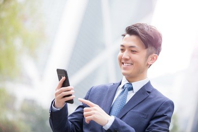 business man use smart phone with business office building background, asian