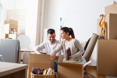 young couple unpacking cardboard boxes at new home.moving house.