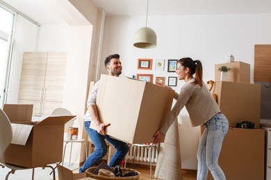 young couple carrying big cardboard box at new home.moving house.