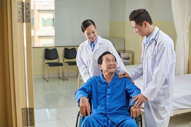 smiling senior patient and doctor talking after surgery
