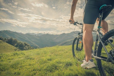 young athletic man riding bike in sunny day in mountain