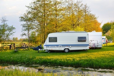 view of caravan trailers parked on a green lawn in a camping on a spring day