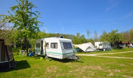 view of caravan trailers parked on a green lawn in a camping on a spring day