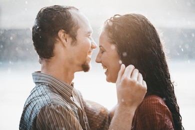 couple in love hugging and kissing under summer rain