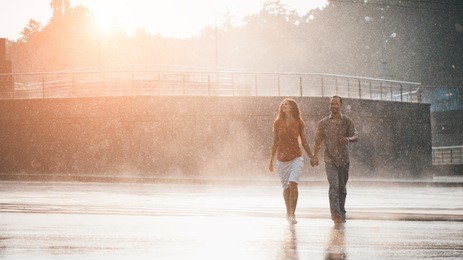 couple in love hugging and kissing under summer rain