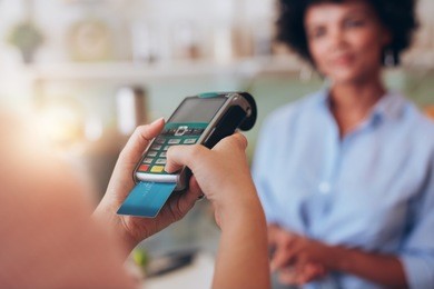 young woman paying by credit card at juice bar. focus on woman hands entering security pin in credit card reader.