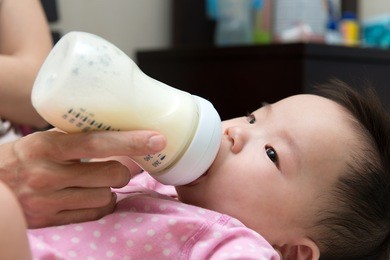 mother feeding baby with milk from a bottle