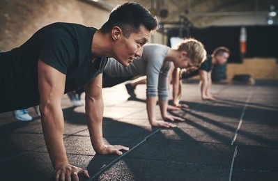 fit young people doing pushups in a gym looking focused