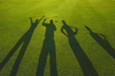 four golfers with open hands silhouette on grass 