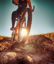a woman riding a bicycle down a dirt trail with big rocks in the back country to get away from the city toned with a retro vintage instagram filter app or action effect 