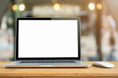 conceptual workspace, laptop computer with blank white screen on table, blurred background.