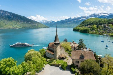 spiez castle with cruise ship on lake thun in bern, switzerland.