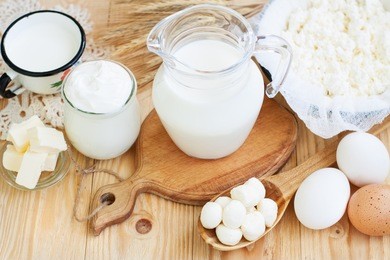fresh dairy products (milk, cottage cheese, sour cream, mozzarella, butter), wheat on light wooden background