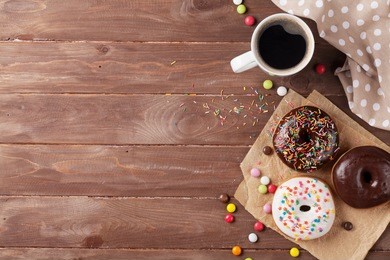 donuts and coffee on wooden table. top view with copy space