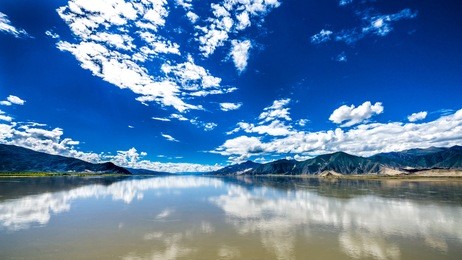 the wide and calm yarlung tsangpo river under the blue cloudy sky in tibet, china