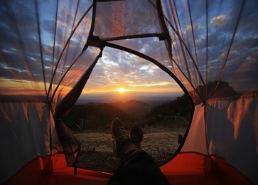a camping tent glows under sunset to a night sky  outdoor camping adventure