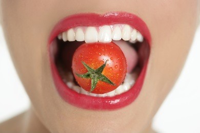 eating a red tomato macro of woman teeth and red lips mouth