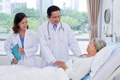 vietnamese doctor and nurse talking to senior patient in ward