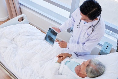 doctor showing lungs x-ray on digital tablet to female patient
