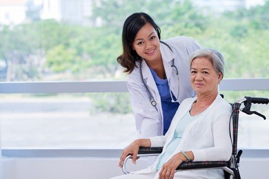 pretty young doctor caring about elderly woman in wheelchair