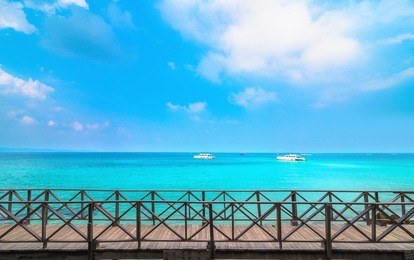 pier extending out over the blue green sea with serenity beach