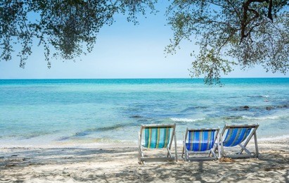 three beach chairs on the white sand beachand tree with clear sky