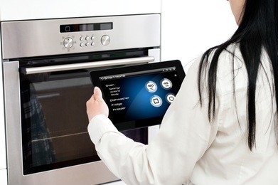woman sets up oven baking programme. conception of using smart home application.
