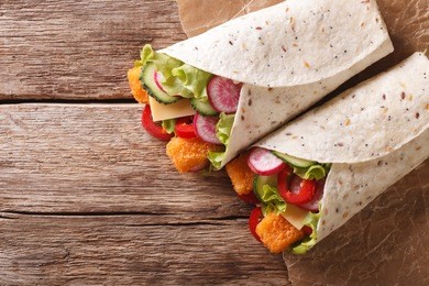 sandwich roll with fish fingers, cheese and vegetables close-up on the table. horizontal view from above