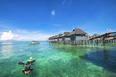 tourists do water rescue in diving training course with dramatic view of crystal clear water and coral in blue sky background at mabul island , sabah, malaysia