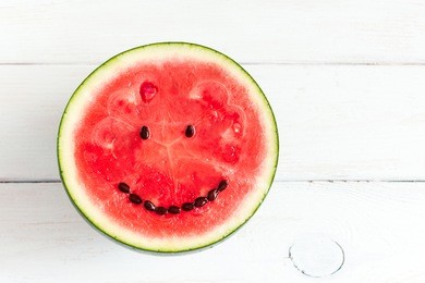 watermelon with smile face. funny watermelon on wooden white background. top view, flat lay, copy space