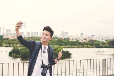young asian man taking selfie on the background of big city