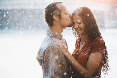 couple in love hugging and kissing under summer rain