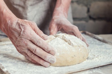 whole grain bread with seeds of sunflower to the oven. hands of the baker men. the process of kneading wheat bread. rustic style. selective focus
