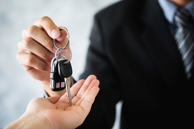 car salesman giving the key to the new car owner transportation and ownership concept.