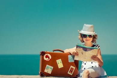 child with vintage suitcase and city map on summer vacation. travel and adventure concept
