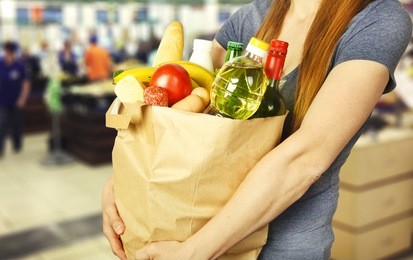 basket with produce in woman hand on background from supermarket