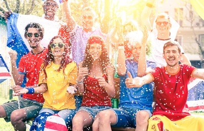 cheering football fans exulting watching match on screen outdoors - sport supporters party and fun for international soccer game - multiracial concept of joy and togetherness  - sun halo filter