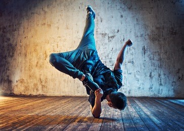 young man break dancing on wall background. blue and red lights effect.