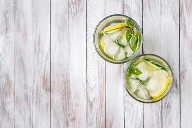 water with lemon, mint and cucumber on the wooden light background. water detox. top view.