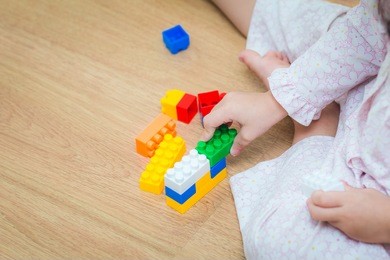 a baby girl play colorful plastic toy blocks before bed