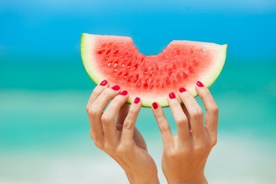 hand holding watermelon on the beach. 