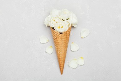 ice cream of rose flowers in waffle cone on light gray background from above, beautiful floral decoration, vintage color, flat lay styling 