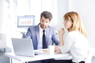 portrait of young banking advisor sitting in front of laptop and helping a client with her banking accounts.