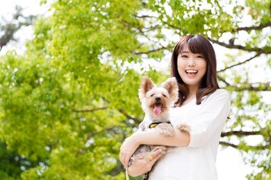 attractive asian woman holding dog in the park