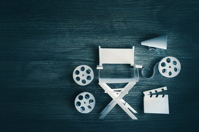 high contrast vintage image of director chair and several movie items made from paper on a wood surface