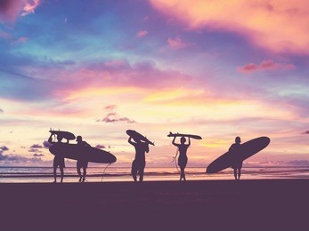 silhouette of surfer people carrying their surfboard on sunset beach, vintage filter effect with soft style