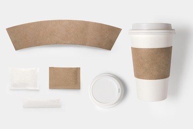 design concept of mockup paper, sugar, coffee creamer, toothpick, lid and coffee cup set on white background. copy space for text and logo. clipping path included on white background.