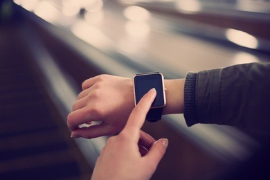 hipster girl use smart wrist watches mobile app riding escalator in metro.always stay connected.big blank empty screen for mobile application logo.stylish gold touchscreen device